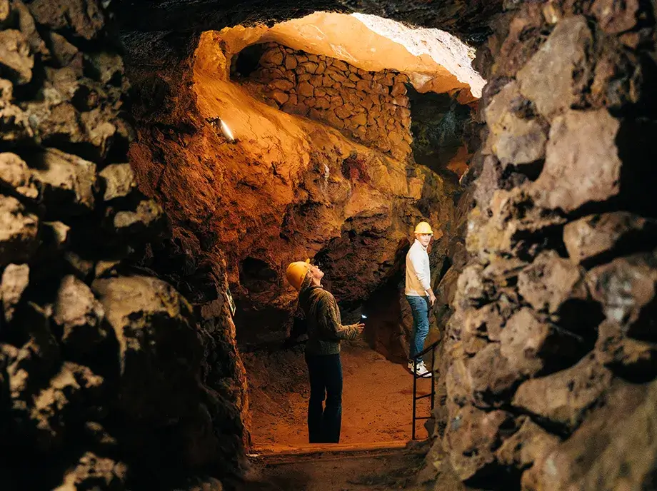 Visitantes con casco recorriendo una galería rocosa del Parc Miner del Maestrat